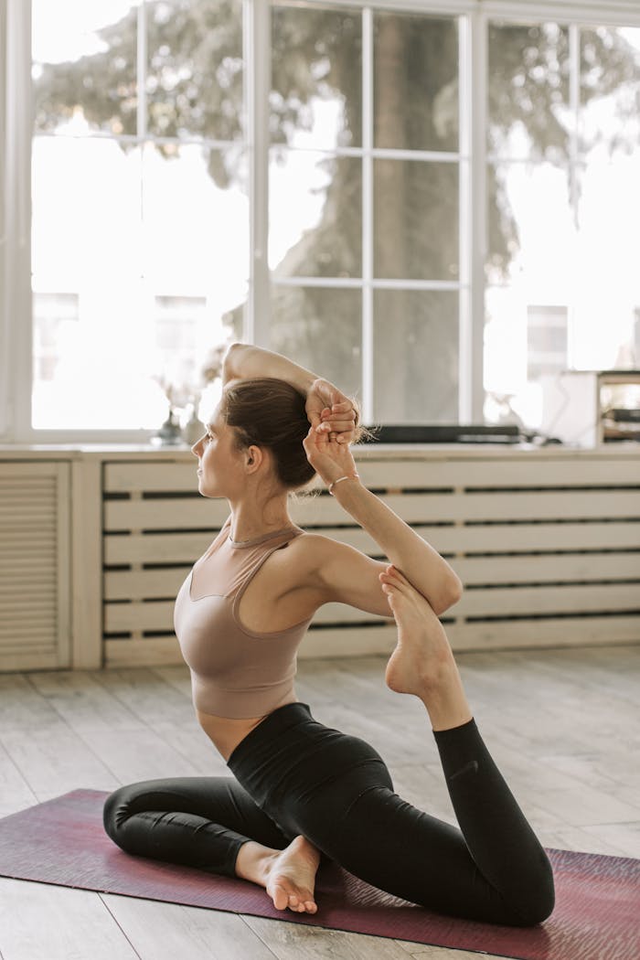 Female practicing yoga in an indoor studio, highlighting flexibility and healthy lifestyle.